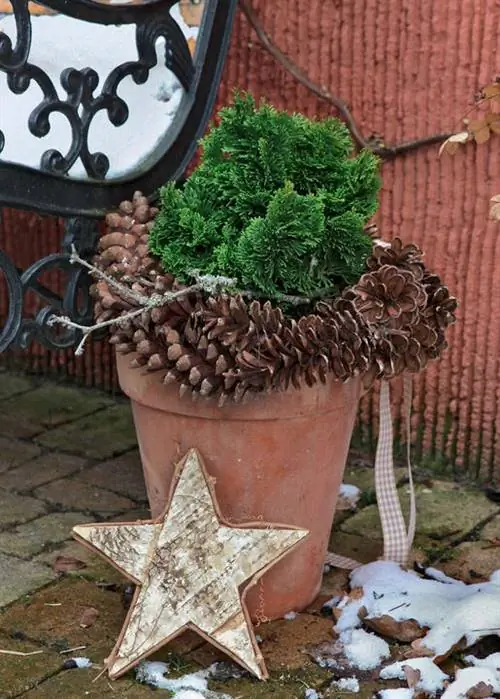 Большой глиняный горшок, украшенный венком из шишек