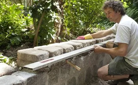 Проверьте выравнивание садовой стены с помощью спиртового уровня.