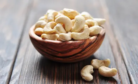 Орехи кешью в миске на деревянной тарелке