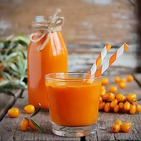 Бутылка и стакан с соком облепихи