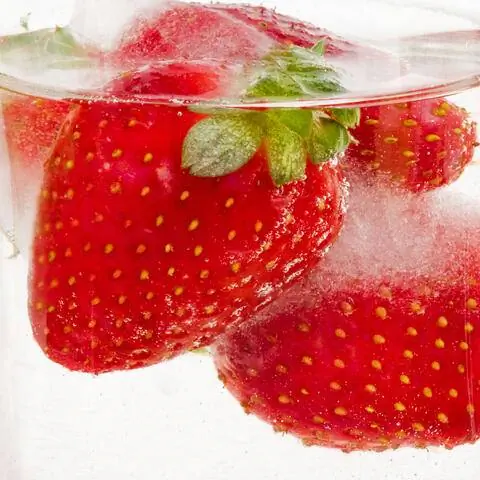 Замороженная клубника в виде кубиков льда в стакане