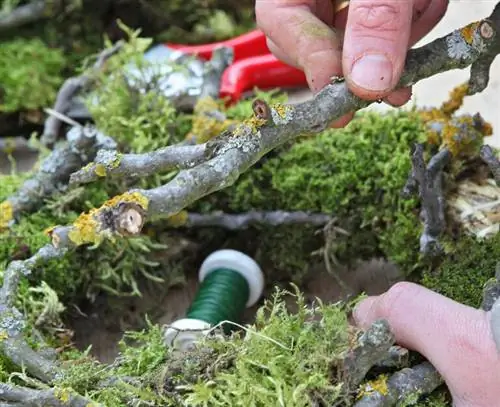 Прикрепите ветки к венку из мха