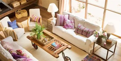 Гостиная с белым диваном, табуретами ручной работы из дерева и цветной ткани, старинным журнальным столиком на колесиках и ковром (00391533 O)