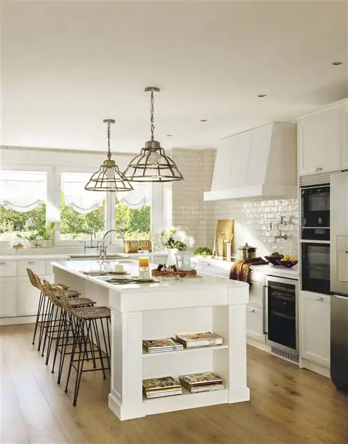 Белая кухня с островом и деревянным полом.