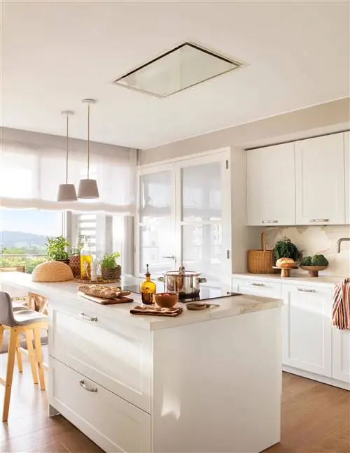 Белая кухня с островом и потолочной вытяжкой.