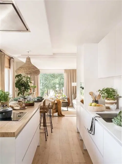 Белая кухня открыта для гостиной с Silestone и деревянными столешницами.