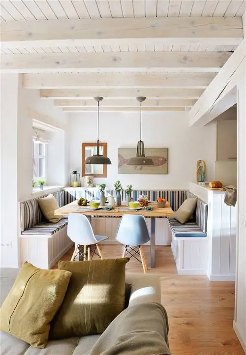 Столовая совмещена с гостиной и кухней в летнем домике с большой скамейкой в U_00417823