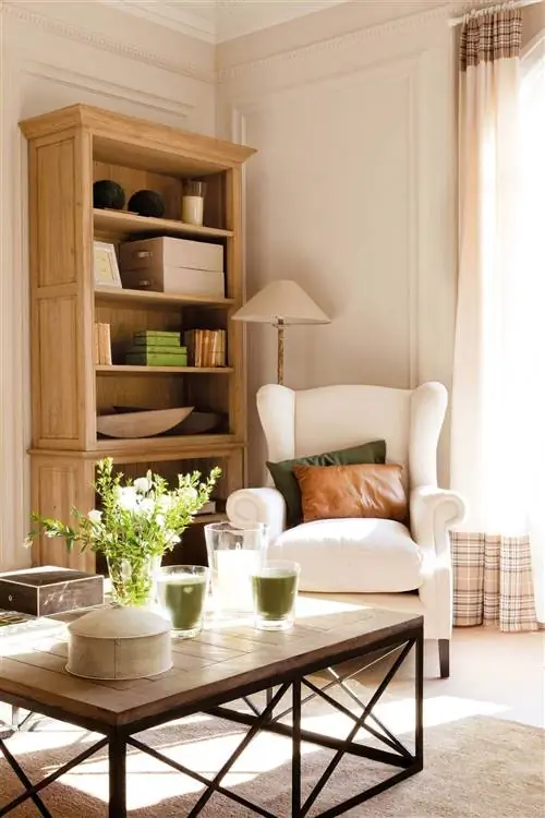 Гостиная с журнальным столиком, деревянным книжным шкафом и белым креслом