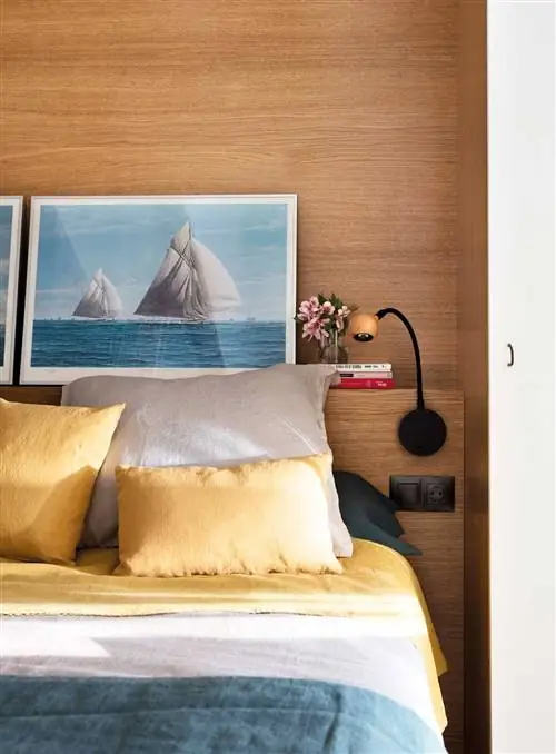 Небольшая спальня с деревянным изголовьем и черными бра