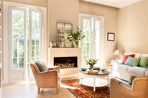 гостиная-с-зажженным-камином-белым-диваном-с-зелеными-и-красными-подушками-и-бежевыми-креслами-и-круглым-журнальным-столиком-на-килиме 00443384