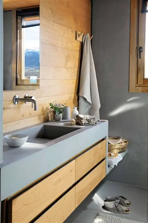 Современная ванная комната с серой столешницей из микроцемента и деревянными ящиками.