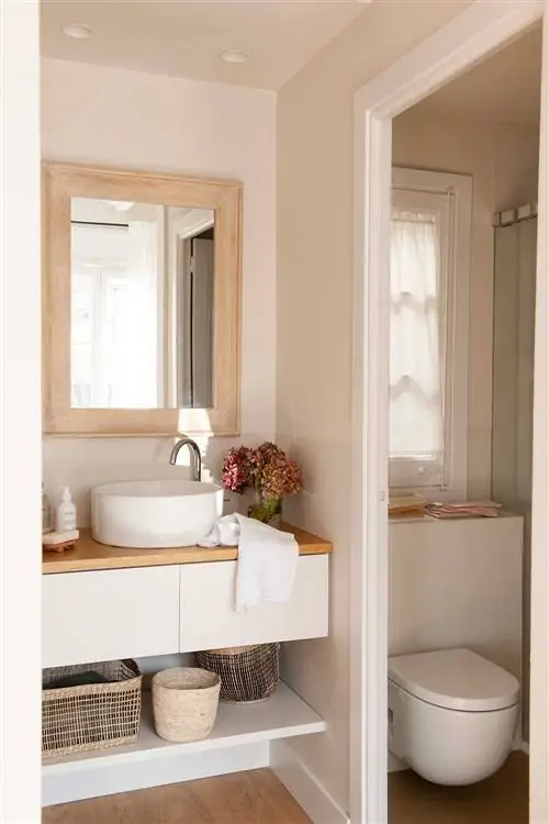 Ванная комната с подвесным белым шкафом и туалетом в кабине.