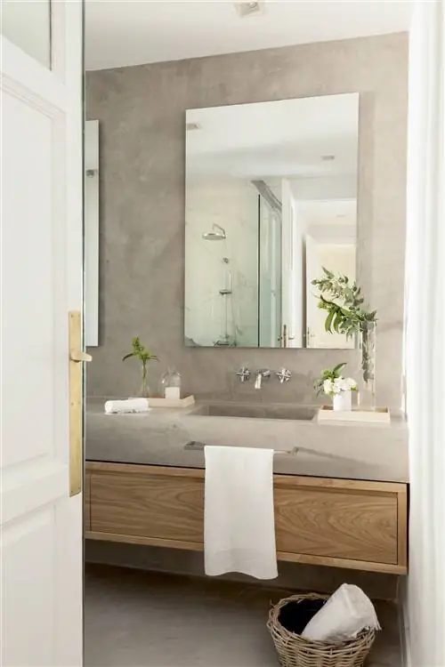 Ванная комната облицована микроцементом и деревянной мебелью.