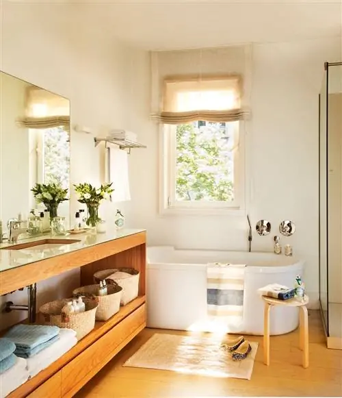 Ванная комната с деревянной мебелью и отдельно стоящей ванной.