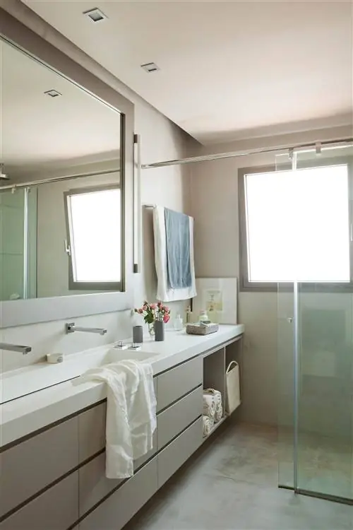 Современная ванная комната с серым шкафом и белой столешницей.