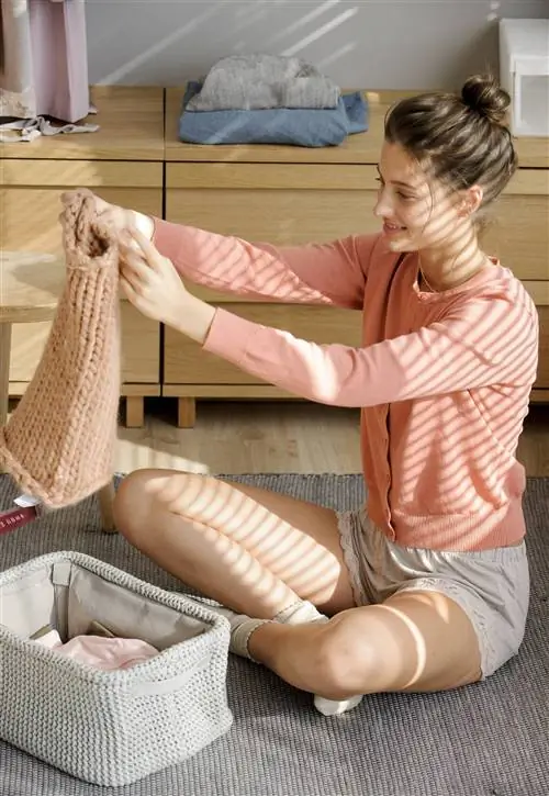 женщина достает свитер из коробки 00443840