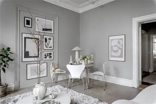 Столовая в скандинавском стиле оформлена в бело-серых тонах с лепниной на потолке.