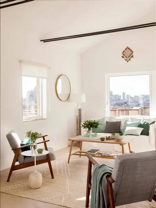 Гостиная с белым диваном, креслами и круглым зеркалом.