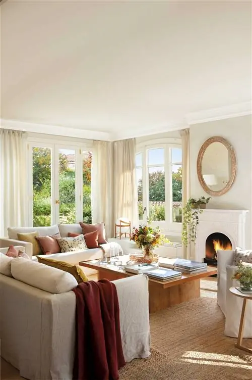 Гостиная с камином, белыми диванами и деревянным столом.