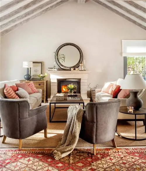 Классическая гостиная с небольшим круглым зеркалом из состаренного металла над камином