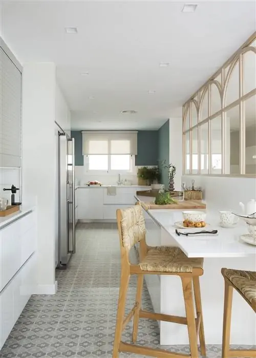 Белая кухня с барной стойкой и зеленой стеной от Pia Capdevila.