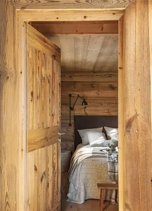 Спальня из дерева с льняным изголовьем и черными бра.