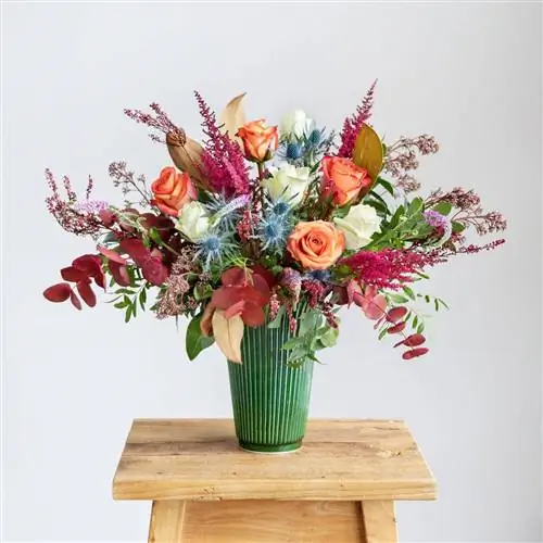 Букет с яркими и яркими цветами и цветами, такими как розы или эвкалипты.