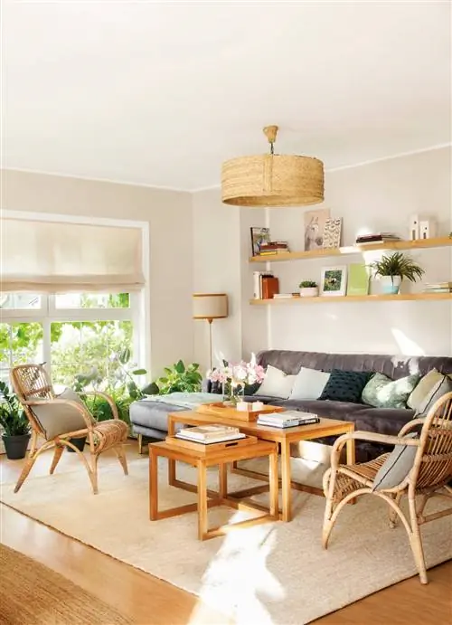 Гостиная с гнездом из деревянных столов, кресел и волоконной лампы.