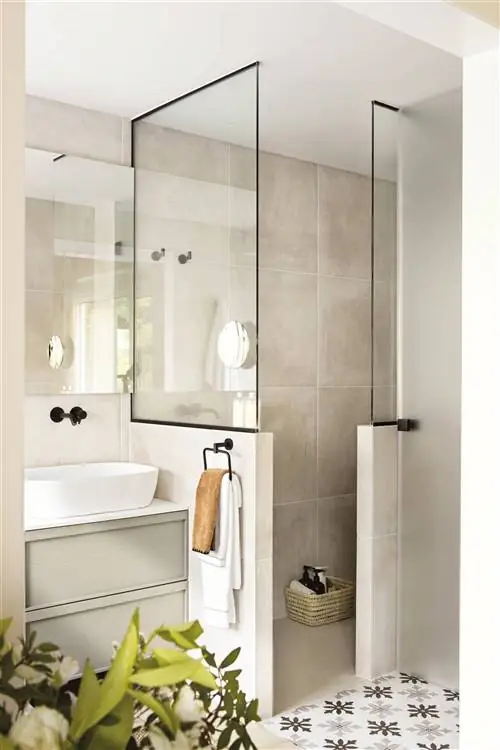 Небольшая ванная комната с душем со стеной и стеклянной панелью.