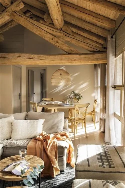 Деревенская столовая с затяжками и льняным диваном и потолком с деревянными балками.