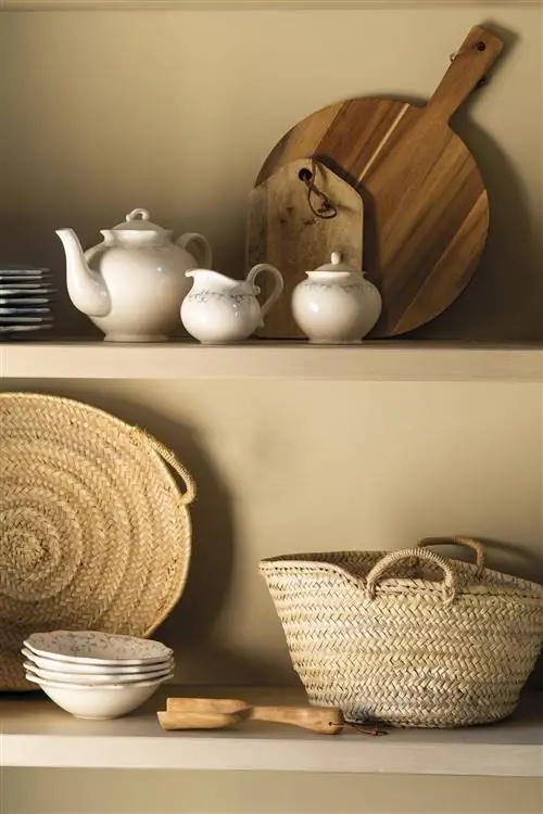 Шкаф с волокнистыми корзинами, фарфоровой посудой и деревянными досками.