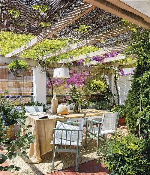 Открытая столовая с беседкой и множеством цветов и растений.