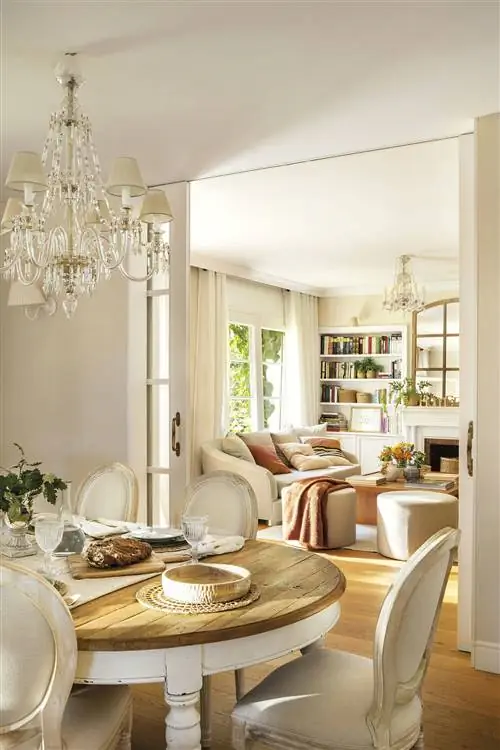Классическая столовая и гостиная с пустым деревянным столом и люстрой.