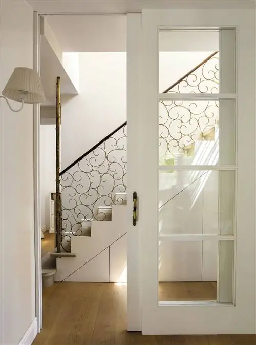 Прихожая со стеклянной дверью и лестницей с золотыми железными перилами.