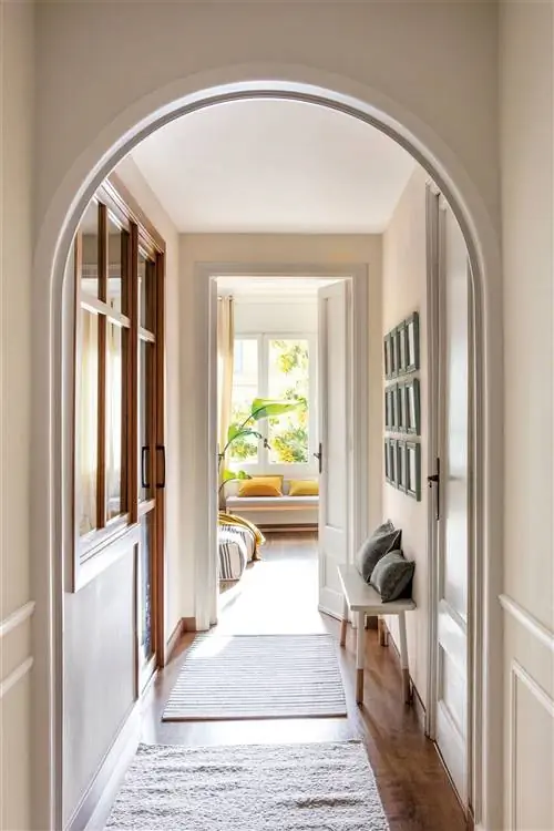 Очаровательная прихожая с картинами и небольшой скамейкой.