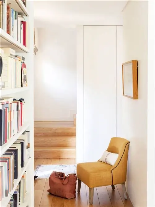 Очаровательный коридор с книжным шкафом и маленьким желтым креслом.
