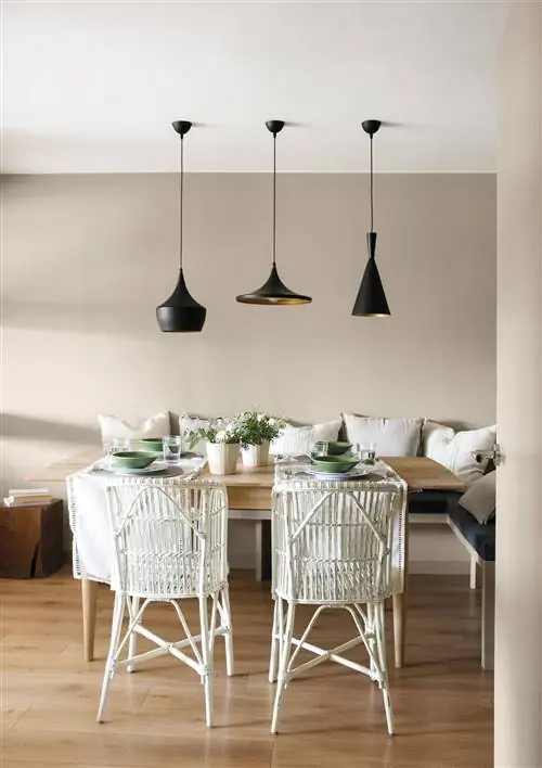 Офис с деревянным обеденным столом, белыми стульями и современными черными лампами.