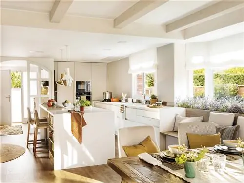 Кухня открыта для столовой в современном стиле, с островом и белой мебелью.