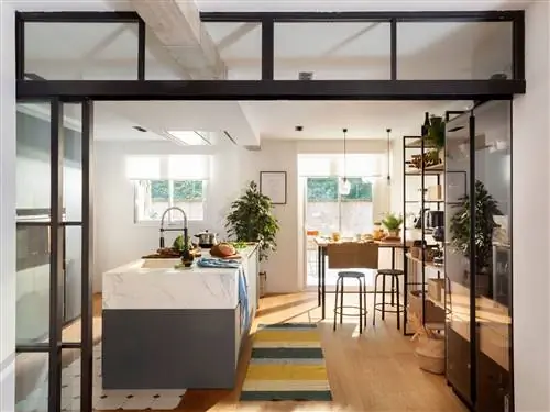 Большая кухня с большим островом с серыми шкафами и столешницей с мраморной отделкой.