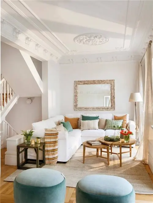 Гостиная с белым диваном, голубыми пуфами и лепным потолком.