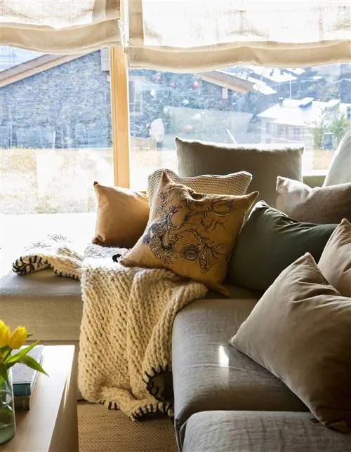 Гостиная с серым диваном, подушками и одеялом.