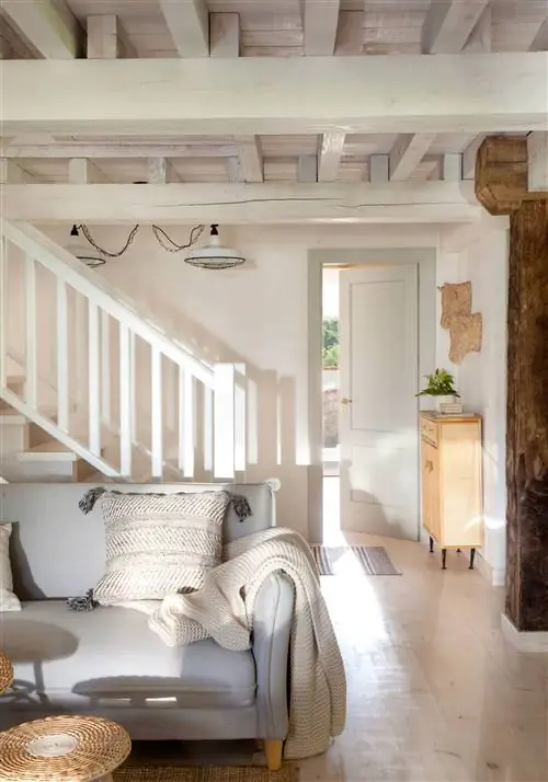 Гостиная с белой лестницей и деревянной консолью.