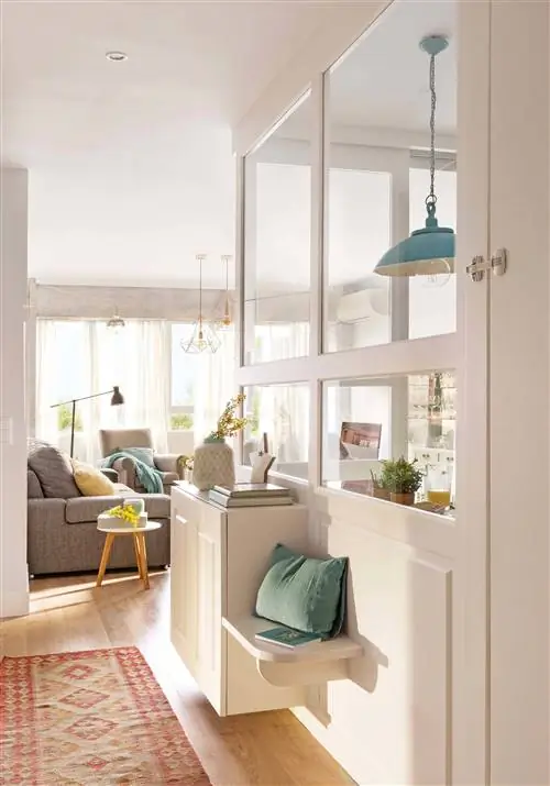 Тумба для обуви в белой прихожей, интегрированной в гостиную.