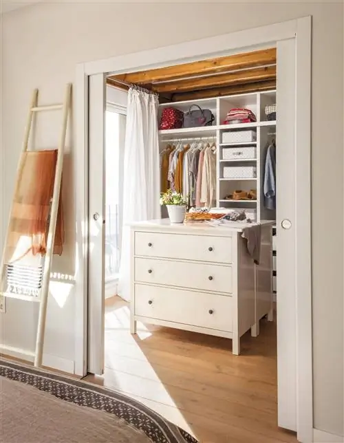 Гардеробная с двумя белыми комодами посередине.