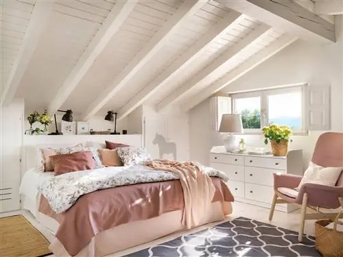Мансардная спальня окрашена в белый цвет с розовым креслом.