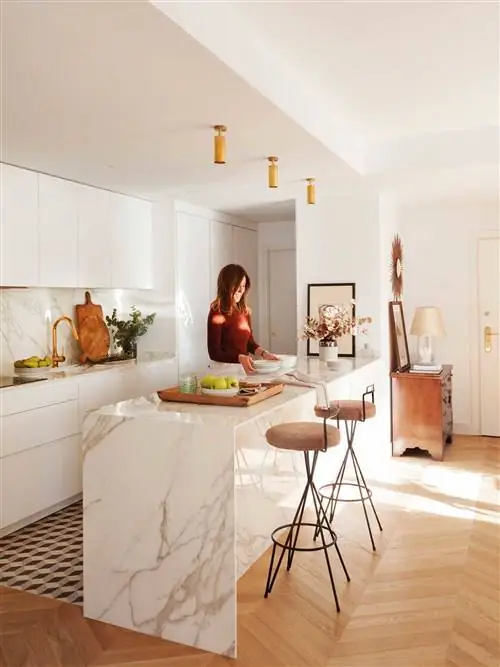 Белая современная кухня с мраморным островом с табуретками.
