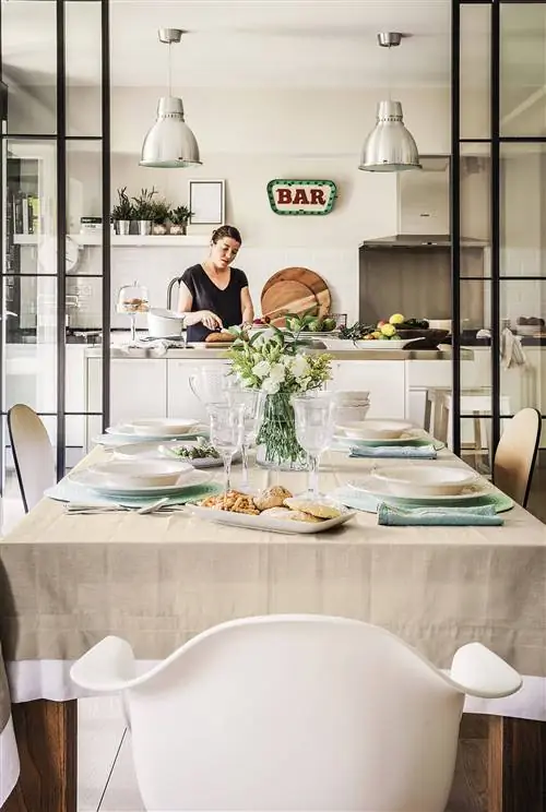 Современная кухня открыта в столовую с застекленной дверью из черного железа, островом и