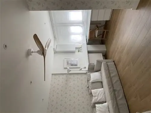 Игровая зона после ремонта в белом цвете с письменным столом, вентилятором и бежевым диваном-кроватью.