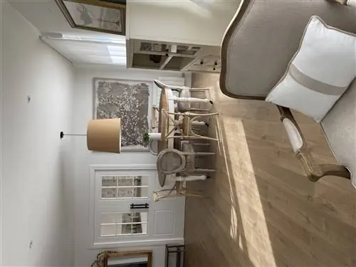 Столовая после ремонта с деревянными полами, серым креслом, кремовым буфетом и обеденным столом с разными стульями.