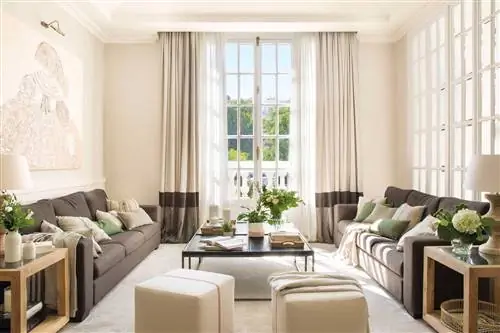 Гостиная с бежевыми стенами и темно-серыми диванами.